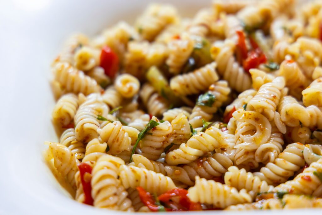 Close-up of a vibrant vegan rotini pasta salad with fresh vegetables.